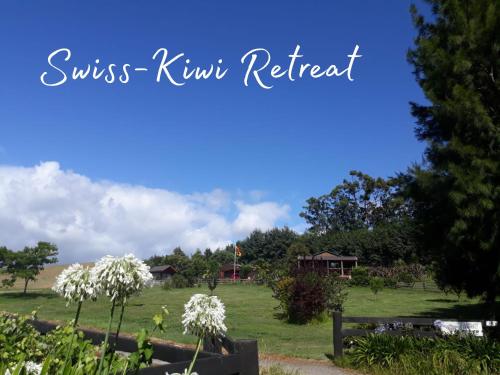a field with white flowers and a blue sky at Swiss-Kiwi Cottage and Retreat, B&B in Tauranga