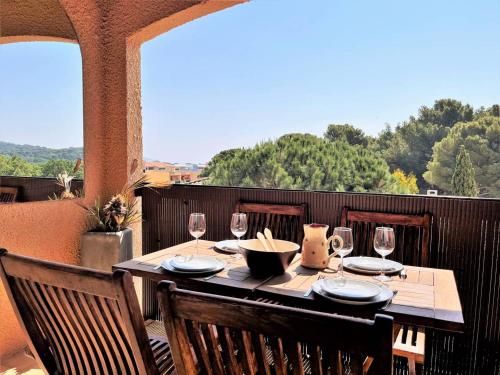 - une table en bois avec des verres à vin sur le balcon dans l'établissement Studio avec terrasse, parking privé proche mer - FR-1-251-506, à Bormes-les-Mimosas