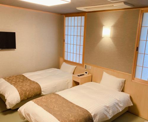 a hotel room with two beds and a tv at Hotel Hanakomichi in Nara