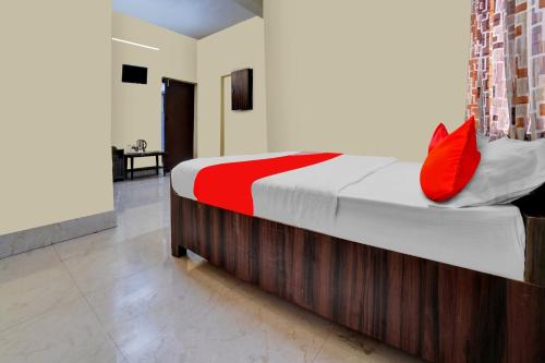 ein Schlafzimmer mit einem Bett mit roten Kissen darauf in der Unterkunft OYO Flagship Prakash Inn in Jamshedpur