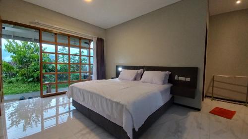 a bedroom with a large bed and a large window at Mountain Ecolodge in Gubukklakah