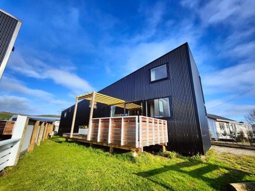 a black house with a deck in a yard at Vitamin Sea Beach House in Riverton