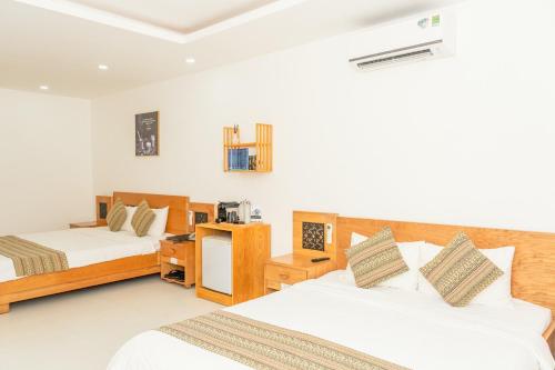 Habitación de hotel con 2 camas y escritorio en Trung Nguyên Coffee Resort, en Buon Ma Thuot