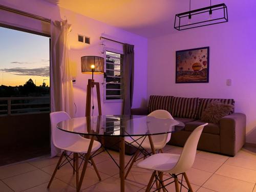 sala de estar con mesa de cristal y sillas blancas en Apartamento Alberdi con amplio balcón en Villa María