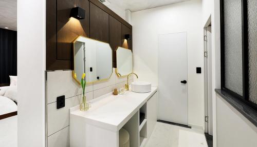 Hotel Intro Chuncheon في تشنتشون: حمام أبيض مع حوض ومرآة