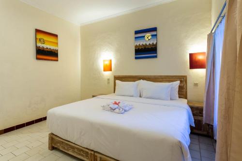a bedroom with a large white bed with flowers on it at Utama Villas Beach Front Candidasa in Candidasa