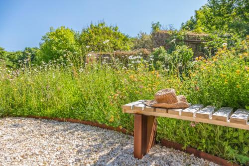 a straw hat sitting on a bench in a garden at Linham Barn in Kingsbridge