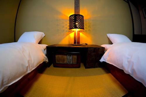 a bedroom with two beds and a table with a lamp at HA-MON Slope Side Hotel and Private Chalet in Otari