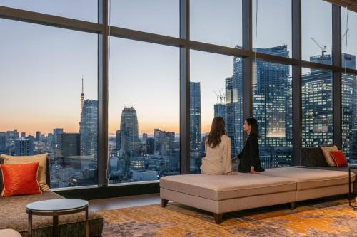 two women sitting on a couch in a room with a large window at THE BLOSSOM HIBIYA in Tokyo