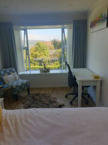 a bedroom with a bed and a desk and a window at New, Cosy & Private 1-Bedroom & Living Flat in Porirua
