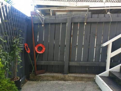 a fence with a gate with a red object on it at New, Cosy & Private 1-Bedroom & Living Flat in Porirua
