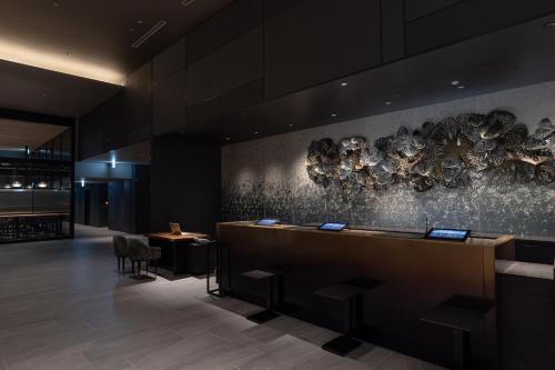 a lobby with a reception desk and a wall with art at THE BLOSSOM HIBIYA in Tokyo