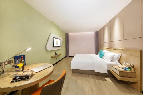 a hotel room with a bed and a desk with a laptop at Qianhai Holiday Hotel in Bao'an
