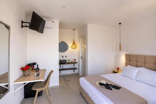 a bedroom with a bed and a desk and a television at Chrysonisos Suites with Sunset & Seaviews near Kini in Ano Syros
