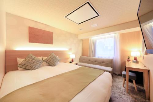 Schlafzimmer mit einem Bett, einem Schreibtisch und einem Fenster in der Unterkunft QuintessaHotel SapporoSusukino63 Relax&Spa in Sapporo