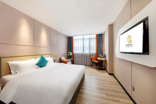 a hotel room with a bed and a flat screen tv at Qianhai Holiday Hotel in Bao'an