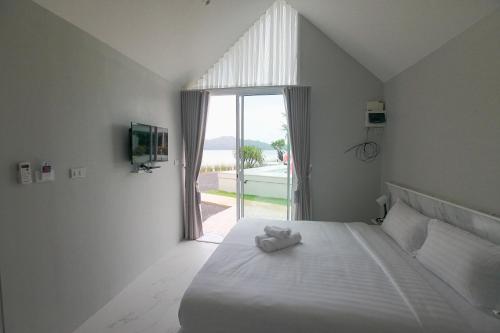 a bedroom with a white bed with a large window at Miami Seaview in Ban Pak Ba Ra
