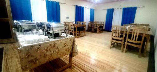 Zimmer mit Tischen, Stühlen und blauen Vorhängen in der Unterkunft Maryoul Guest House, Hunder Nubra in Hundar