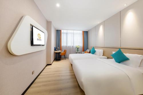a hotel room with two beds and a tv at Qianhai Holiday Hotel in Bao'an