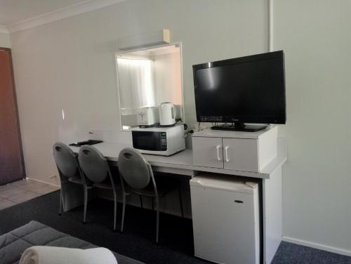 a room with a desk with a television and chairs at Forster Palms Motel in Forster