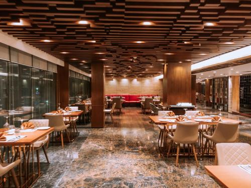 a restaurant with tables and chairs in a room at The Peninsula Chittagong Limited in Chittagong