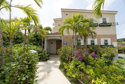 a house with palm trees and flowers in front of it at Ecot Shimozato 3 in Miyako Island