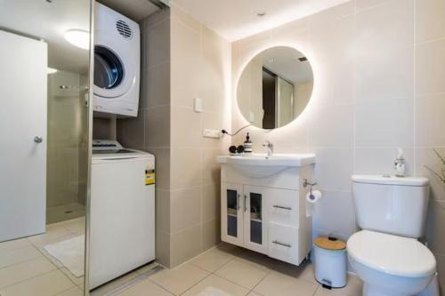 uma casa de banho com um WC, um lavatório e um espelho. em Longbeach Luxe, Surfers Paradise em Gold Coast