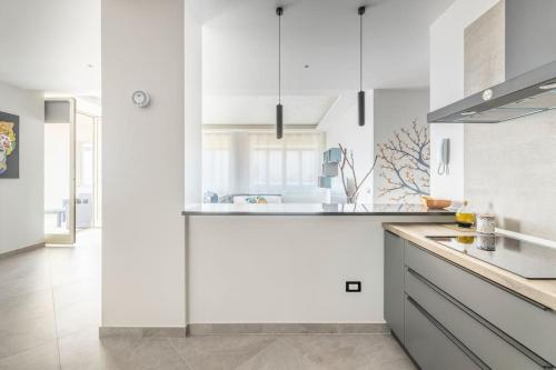 a white kitchen with white cabinets and a sink at Blu Mediterraneo - Seaview luxury house in Acitrezza