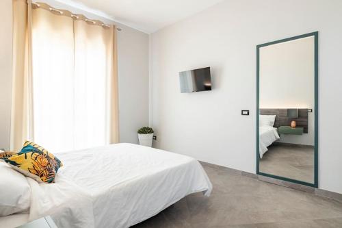 a bedroom with a large white bed and a mirror at Blu Mediterraneo - Seaview luxury house in Acitrezza