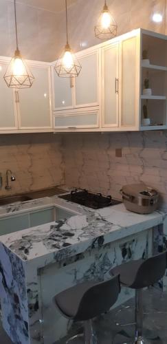 eine Küche mit weißen Schränken und einer Marmoroberfläche in der Unterkunft VILLA DUANA BATU TOP VIEW with indoor privat pool, PS 5, billiard, and rooftop 360 mountain view in Batu