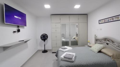 um quarto branco com uma cama e uma televisão na parede em Apartamento Privado SOL em Tarija