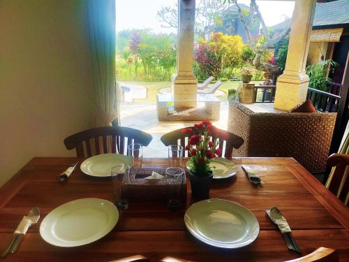 a wooden table with plates and utensils on top of it at 3BRBeautifull Villa Queen With Stunning Rice Field in Saba