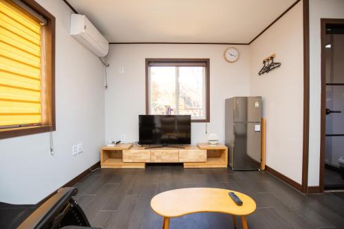 a living room with a tv and a table and a refrigerator at Yangyang Naksan Bamgol Land in Yangyang