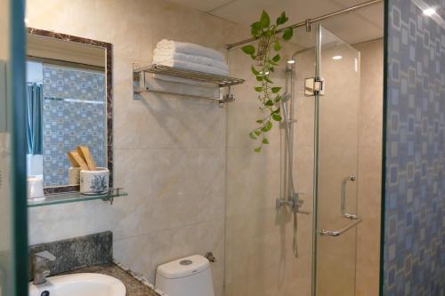 y baño con ducha, aseo y lavamanos. en MH Hanoi Hotel, en Hanói