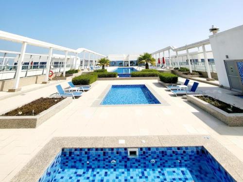 una piscina con sillas y un edificio en Beach Dream - a luxury 1 bedroom apartment with direct beach access en Ras al-Jaima