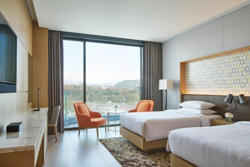 a hotel room with two beds and a large window at Marriott Jeju Shinhwa World Hotel in Seogwipo