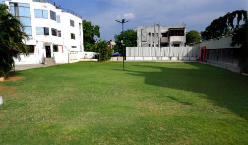 a large yard with a white building and a fence at Hotel Kewal in Nashik