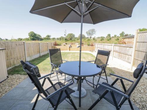 a table with chairs and an umbrella on a patio at 14 Parc Delfryn in Brynteg
