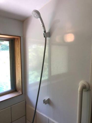 a shower in the corner of a bathroom with a window at BEACH HOUSE OHAMA in Kuranomoto