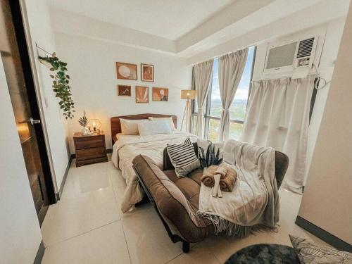 um quarto com uma cama e um sofá em frente a uma janela em Chic and Cozy Studio Viceroy Residences Taguig em Manila