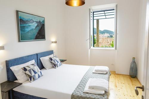 a white bedroom with a large bed and a window at PORT - unique apartment in Dubrovnik
