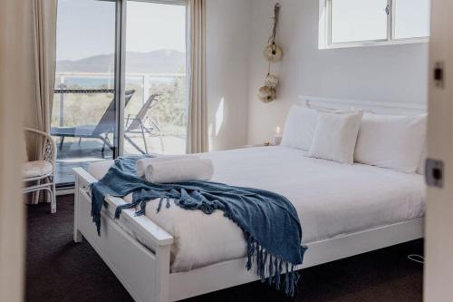 1 dormitorio con cama blanca y balcón en Seymour Waves ~ Absolute Serenity, en Bicheno