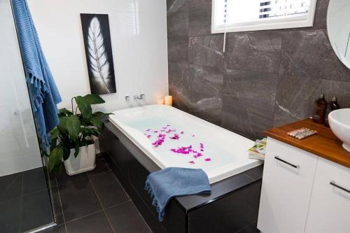 ein Badezimmer mit einer Badewanne mit rosa Blumen darauf in der Unterkunft 5 Bed Mooloolaba Getaway in Mooloolaba