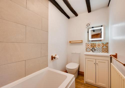 a bathroom with a white tub and a toilet at Coach House in Llanfachreth