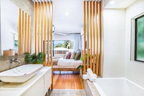 uma casa de banho com uma banheira e um quarto com uma cama em The Orchard House - Luxury Villa on a Sprawling Tropical Acreage em Redlynch