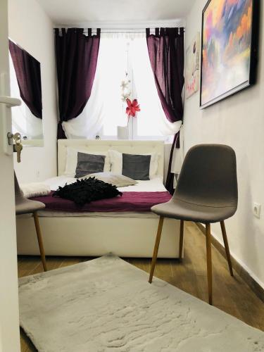 1 Schlafzimmer mit einem Bett mit einem Fenster und 2 Stühlen in der Unterkunft Central Petit Room in Braşov