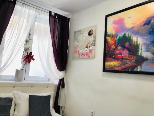 ein Schlafzimmer mit einem Fenster und einem Gemälde an der Wand in der Unterkunft Central Petit Room in Braşov