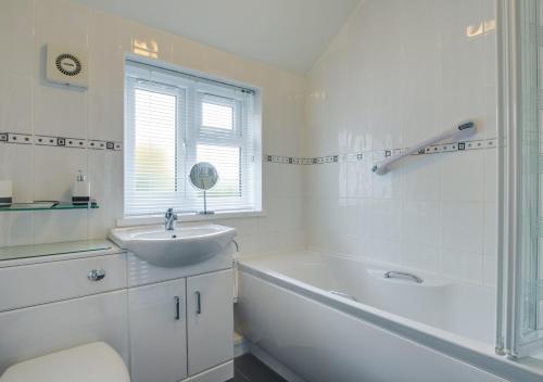 a white bathroom with a tub and a sink and a bath tub at Y Bwthyn in Abererch