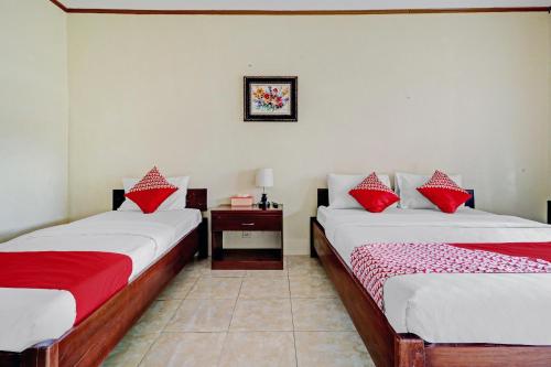 2 camas en una habitación con almohadas rojas y blancas en Collection O 90461 Graha Atmadja Syariah Guest House, en Bandung