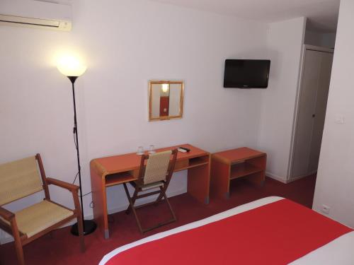 Cette chambre comprend un bureau, une table et des chaises. dans l'établissement Hotel Tennis International, au Cap d'Agde